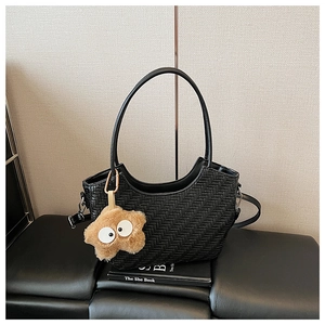 Détail du sac cabas tressé noir avec breloque étoile et poignées rondes élégantes