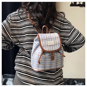 Light blue plaid canvas backpack with drawstring closure and brown leather trim detailing