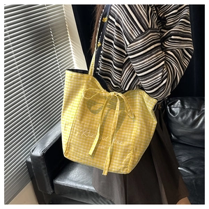 Close-up of yellow checkered canvas tote bag with bow tie and Rise and Shine text