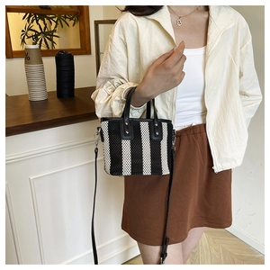 Détail du mini sac seau tressé à rayures noires et blanches avec bandoulière en cuir
