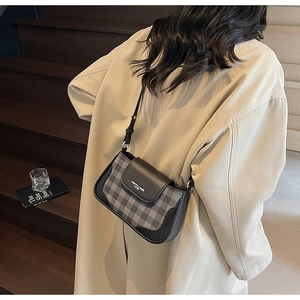 Detail of crossbody bag with black grey checkered pattern and leather trim on flap