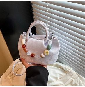 Détail du sac seau plissé lilas avec une chaîne décorative en perles multicolores