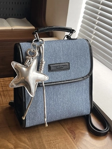 Retro denim shoulder bag with black leather trim and silver star charm on desk
