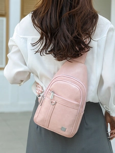 Pink minimalist chest bag with textured strap shown on model against a soft wall background
