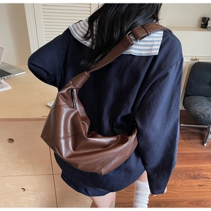 Vue détaillée du sac bandoulière croissant marron foncé avec sangle épaisse et coutures