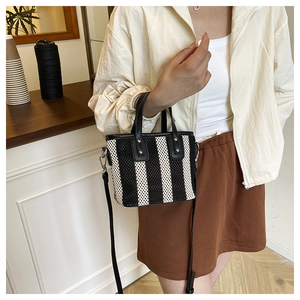 Détail du mini sac seau tissé avec bordure en cuir noir et rivets métalliques argentés