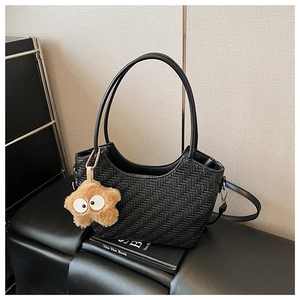 Détail d'un sac cabas noir tressé avec un charmant pendentif étoile en peluche sur l'anse