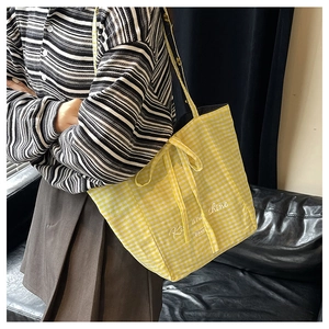 Detail of yellow checkered canvas tote bag with Rise and Shine text and bow closure