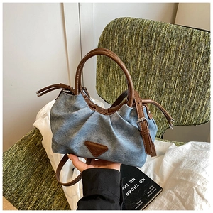 Detail of blue denim shoulder bag showing retro brown leather logo and drawstring