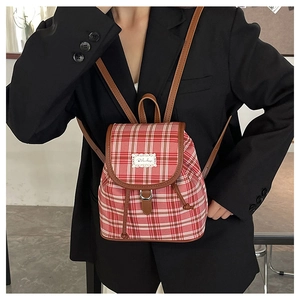 Detail of red checkered backpack with brown leather trim and lace logo on front flap