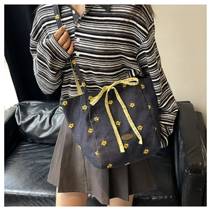 Detailed embroidery of yellow flowers and a plaid bow on a navy canvas tote bag