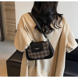 Detail of minimalist black plaid underarm bag with leather strap and logo flap