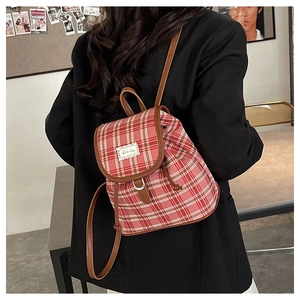 Detail of red and pink plaid mini backpack with lace trim and leather straps on model