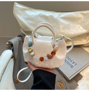 Détail du sac seau plissé blanc crème avec poignée décorative en perles de résine