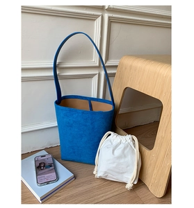 Detail of royal blue matte bucket bag showing drawstring canvas inner pouch and suede texture