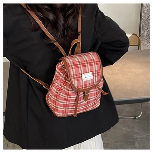 Detail of red and white checkered backpack with premium brown leather straps on a model