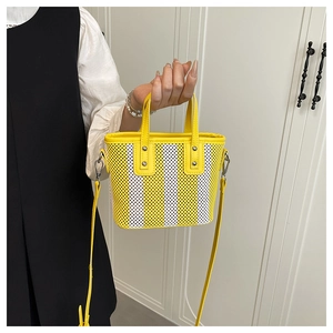 Détail du mini sac cabas en maille rayée jaune avec poignées en cuir et boucles en métal