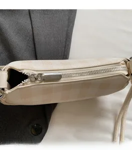 Détail du zip en métal argenté sur un sac bandoulière à carreaux crème et beige poli
