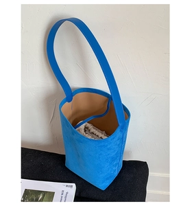 Detail view of royal blue suede bucket bag with beige drawstring lining and wide strap