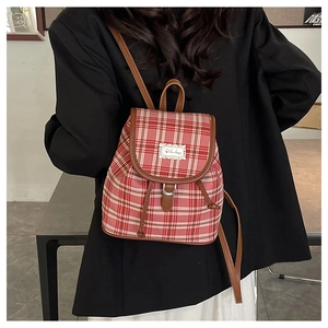 Close-up of red plaid canvas backpack with brown leather trim on female model back