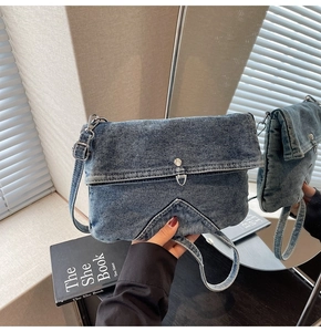 Detail of blue denim crossbody bag with V-shaped stitching and metallic buckle
