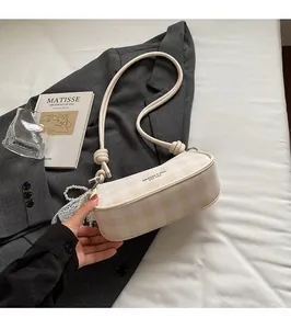 Détail du sac bandoulière à carreaux crème avec breloque en dentelle de perles et logo imprimé