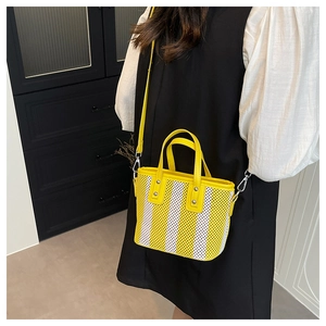 Détail du sac seau bandoulière en maille rayée jaune et blanc porté avec une tenue chic
