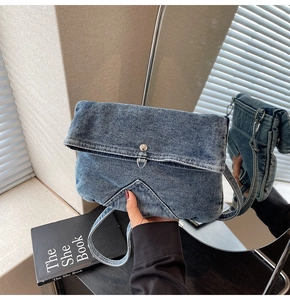 Detailed view of vintage denim crossbody bag featuring flap closure and triangle stitching