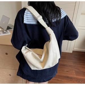 Detailed view of cream crescent crossbody bag with adjustable strap and smooth leather finish