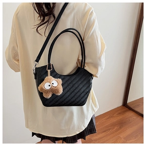 Détail du sac cabas tressé noir avec un charme étoile en peluche et bandoulière
