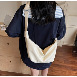 Rear view of a cream white croissant bag with pebble leather texture and wide strap
