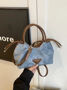 Retro denim pleat handbag with brown leather trim and metal logo in a modern setting