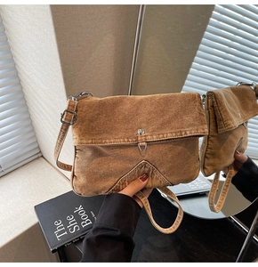 Detail view of vintage brown denim crossbody bag with metal buckle and stitching