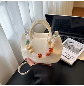 Détail du sac seau blanc crème avec chaîne décorative en perles de résine colorées