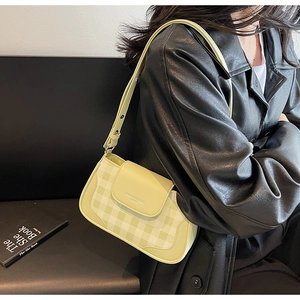 Detail of green and white checkerboard baguette bag with adjustable leather strap