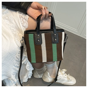 Détail d'un sac seau tissé à rayures avec poignées en similicuir et rivets en métal
