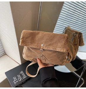 Close-up of vintage brown denim messenger bag showing textured fabric and metal buckle