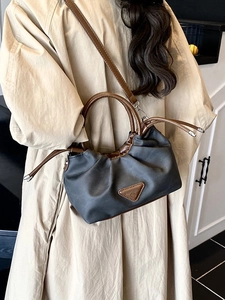 Chic pleated cloud shoulder bag in grey and brown worn with a trench coat