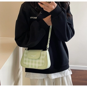 Close-up of green checkered crossbody bag featuring a flap with fashion logo text