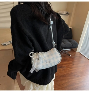 Détail du sac croissant à carreaux bleus avec nœud en perles et charme en dentelle