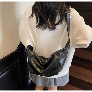 Rear view of model wearing a black leather crescent crossbody bag with wide strap