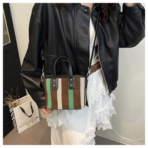 Détails de la texture tricotée du sac seau rayé avec finitions en cuir noir et rivets