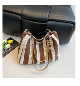 Detail of striped woven tote bag with leather strap and silver metal chain connection