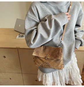 Detail of vintage washed denim crossbody bag featuring a metal buckle and brown strap