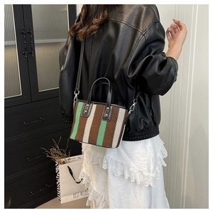 Détail d'un mini sac cabas tissé avec des rayures verticales vertes, blanches et brunes