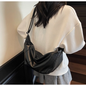 Detail of black pleated crescent crossbody bag showing large capacity and soft texture