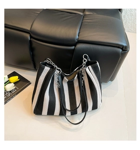 Detailed macro view of black and white striped woven tote bag with metal chain strap