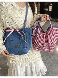Plaid canvas tote bag with cherry embroidery and bow detail shown in lifestyle view