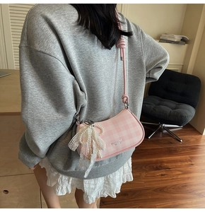 Détail du sac sous le bras à carreaux roses avec nœud en dentelle et perles blanches