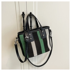 Détail du sac cabas tissé à rayures noires, vertes et blanches avec boucles en métal argenté
